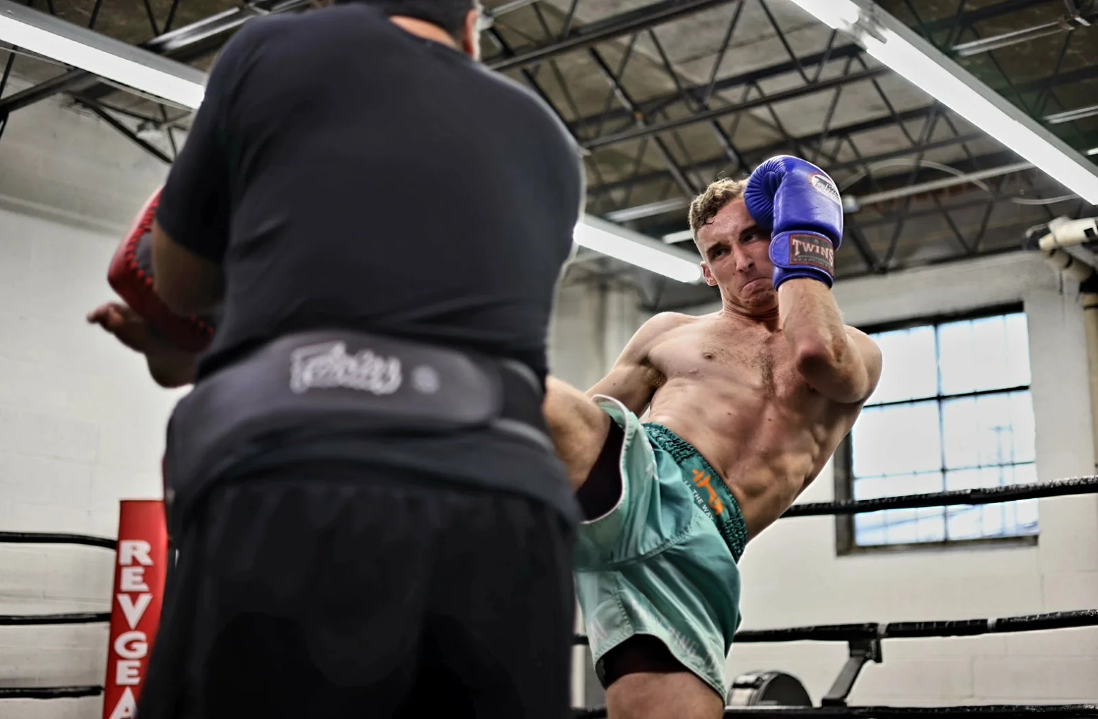 Michael throwing a head kick in a muay thai ring