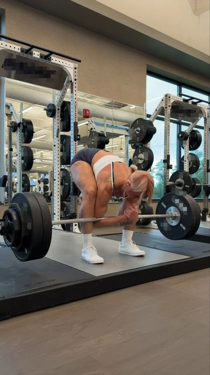 A woman pulling a loaded barbell from the floor