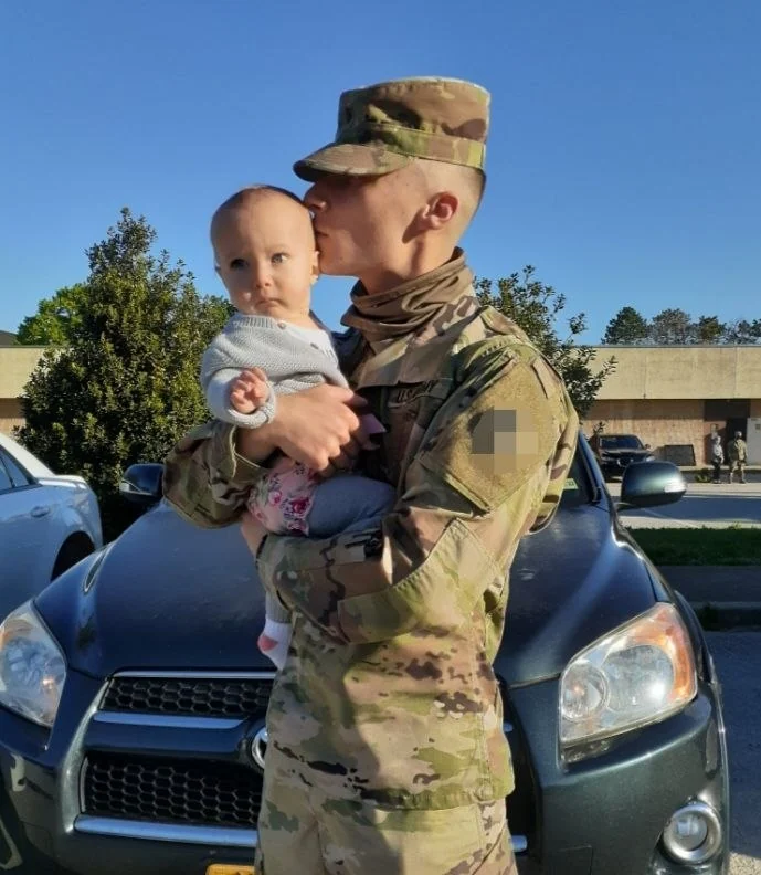 Michael in uniform holding one of his daughters